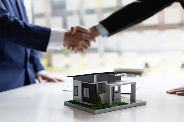 Apretón de manos entre asesor inmobiliario y cliente durante cierre de venta de casa moderna en Queretaro